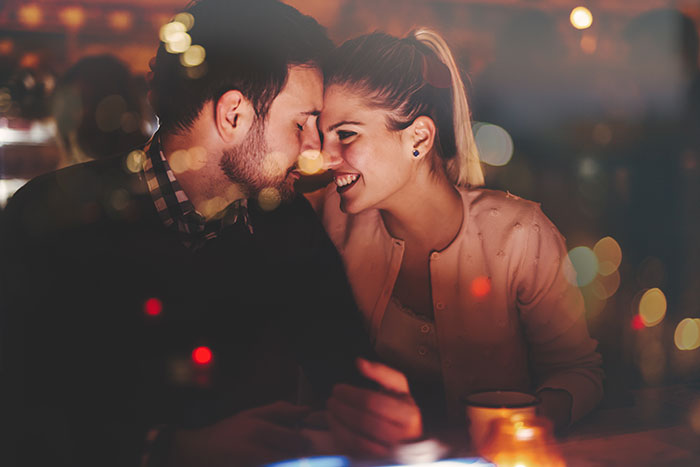 Couple Smiling at one another over drinks